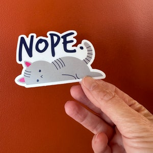 May include: A sticker with a gray cat lying down and the word "NOPE" in blue letters.