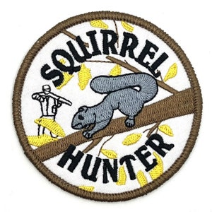 Puede incluir: Un parche bordado blanco con un borde marrón. El parche presenta una ardilla de dibujos animados en una rama con hojas, una persona con un arma y el texto "Squirrel Hunter".