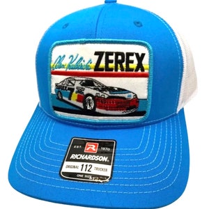 Pode incluir: Um chapéu de caminhoneiro azul e branco com um remendo que apresenta um carro de corrida e o texto "Alan Kulwicki Zerex". O chapéu tem uma etiqueta Richardson 112.