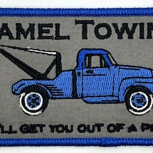 May include: A gray and blue embroidered patch with a tow truck and the text "CAMEL TOWING WE'LL GET YOU OUT OF A PINCH".