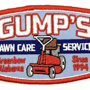 Op de afbeelding: Een geborduurde patch in rood, wit en blauw met de tekst "GUMP'S LAWN CARE SERVICES Since 1994" en een cartoon afbeelding van een zitmaaier. De tekst "Greenbow Alabama" is ook inbegrepen.