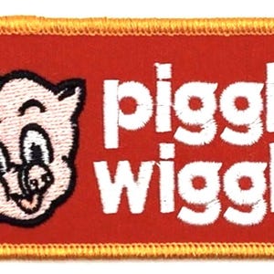 Può includere: Una toppa rettangolare rossa con un maiale ricamato in bianco che indossa un cappello bianco e il testo "Piggly Wiggly" in bianco con un simbolo di marchio registrato.