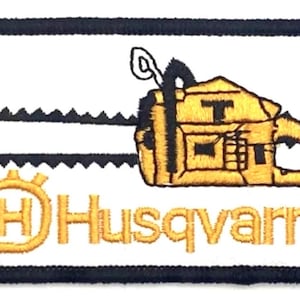 Może przedstawiać: Biała naszywka haftowana z żółtą piłą łańcuchową i napisem "Husqvarna" w kolorze żółtym z żółtym logo w postaci koła z literą "H" w środku.