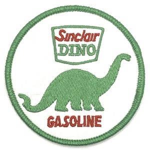 Peut inclure: Un patch brodé vert et rouge sur fond blanc. Le patch représente un dinosaure vert avec le texte "Sinclair Dino Gasoline" en rouge.