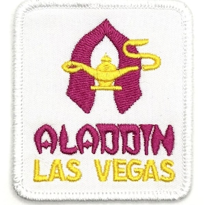 May include: White embroidered patch with a pink genie lamp and the words "Aladdin Las Vegas" in yellow.
