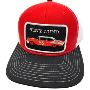 May include: Red and black trucker hat with a white mesh back. The hat features an embroidered patch with a red car and the text "TINY LUND 55".
