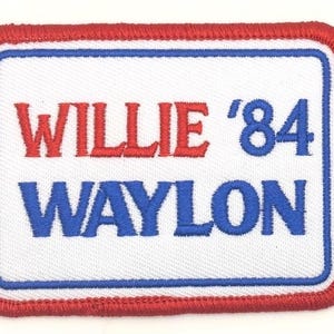 May include: Embroidered patch with the words "WILLIE '84 WAYLON" in red and blue lettering. The patch has a white background with a blue border and a red stitched edge. The patch is rectangular.