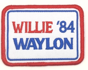 May include: Embroidered patch with the words "WILLIE '84 WAYLON" in red and blue lettering. The patch has a white background with a blue border and a red stitched edge. The patch is rectangular.
