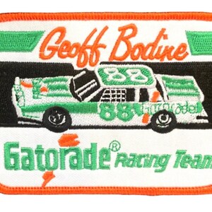 May include: A white, green, and black embroidered patch featuring a race car with the number 88 on it. The text "Geoff Bodine" and "Gatorade Racing Team" are also on the patch.