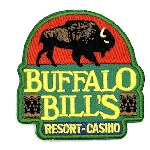 May include: Embroidered patch featuring a brown and black buffalo silhouette against a red and orange sunset. The text "BUFFALO BILL'S RESORT-CASINO" is in yellow lettering on a green background.