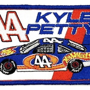 May include: A blue and white embroidered patch featuring a race car with the number 44 on the side. The car is labeled "Hot Wheels" and the text "Kyle Petty" is above the car.