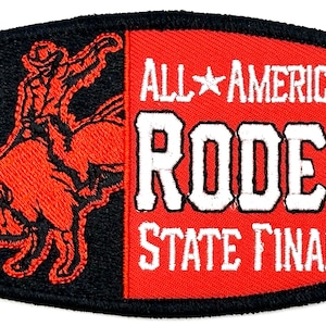 Può includere: Toppa ricamata rossa e nera con un cowboy che cavalca un toro infuriato sul lato sinistro e il testo "ALL*AMERICAN RODEO STATE FINALS" sul lato destro.