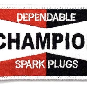 May include: A white patch with red and black borders. The patch has the text "Dependable Champion Spark Plugs" in black lettering.