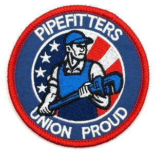 May include: Embroidered patch with a red border, featuring a blue circle with the text "PIPEFITTERS" and "UNION PROUD". Inside, a worker in blue overalls holds a wrench, set against a red and white striped background and stars.