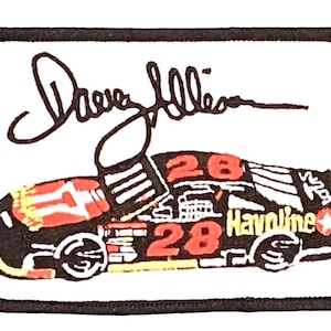 May include: A black and red race car with the number 28 on the side. The car is sponsored by Havoline and has a white star on the side. The car is on a white background with a black border. The signature "Dave Allison" is above the car.