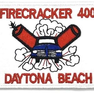 May include: White embroidered patch with red text "Firecracker 400 Daytona Beach". The patch features a cartoon car with two red firecrackers attached to the front, with smoke coming out of the back.