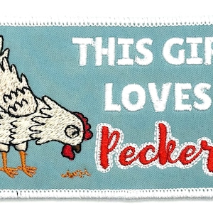 May include: An embroidered iron-on patch with a white chicken pecking at the ground. The patch has a blue background with white text that reads "This Girl Loves Peckers" in red lettering.