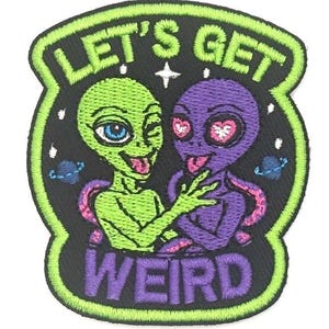 Puede incluir: Parche bordado con dos extraterrestres de dibujos animados. Uno es verde con un ojo azul y guiñando, el otro es morado con ojos en forma de corazón. El parche tiene el texto "LET'S GET WEIRD" en blanco y morado.