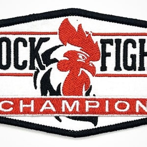 May include: White embroidered patch with a black border. The patch features a red rooster with a black comb and wattle. The text "COCK FIGHT CHAMPION" is embroidered in black on the patch.