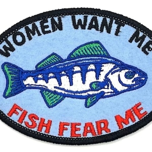 May include: An oval-shaped embroidered patch with a blue and white fish with green fins. The text "Women Want Me Fish Fear Me" is embroidered around the fish.