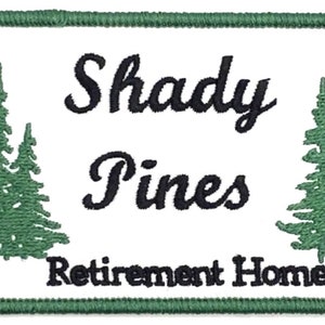 Puede incluir: Un parche rectangular blanco con un borde verde. El texto "Shady Pines Retirement Home" está bordado en negro. Dos pinos verdes están bordados a cada lado del texto.