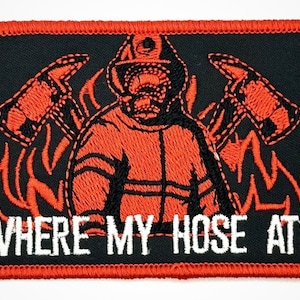 Puede incluir: Un parche bordado con un bombero con un uniforme naranja sosteniendo un hacha. El bombero está rodeado de llamas y el texto "WHERE MY HOSE AT?" está escrito en blanco debajo de la imagen.