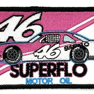 May include: A pink and white race car with the number 46 on the side. The car is on a white background with a pink diagonal stripe and the words "Superflo Motor Oil".