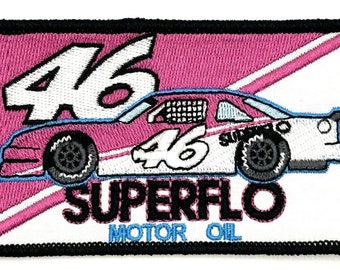 May include: A pink and white race car with the number 46 on the side. The car is on a white background with a pink diagonal stripe and the words "Superflo Motor Oil".
