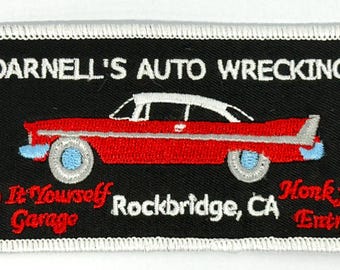 May include: A black and white embroidered patch with a red car and the text "Darnell's Auto Wrecking", "Do It Yourself Garage", "Rockbridge, CA", and "Honk for Entry".