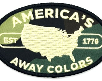 May include: A black and green oval patch with white embroidered text. The text reads "America's Est 1776 Away Colors" and features a white outline of the United States.