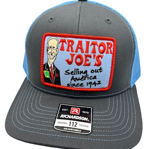 May include: A gray and blue trucker hat with a red, white, and blue embroidered patch that says "TRAITOR JOE'S Selling out America since 1942". The hat has a Richardson 112 label.