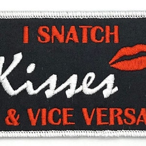 May include: A black embroidered patch with white stitching around the edges. The patch says "I snatch kisses & vice versa" in red and white lettering with a red embroidered lip print.