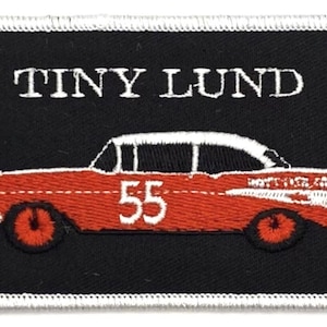 May include: A black and white embroidered patch with a red car and the text "TINY LUND" in white. The car has the number "55" on the side.