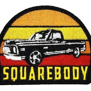 May include: Embroidered patch with a black pickup truck silhouette set against an orange, yellow, and red sunset gradient. The word "SQUAREBODY" is embroidered in yellow block letters at the bottom, with a black border.