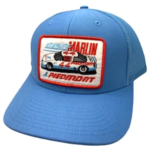 May include: A light blue trucker hat with a red, white and blue embroidered patch featuring a racing car with the text "Sterling Marlin" and "Piedmont" on it.