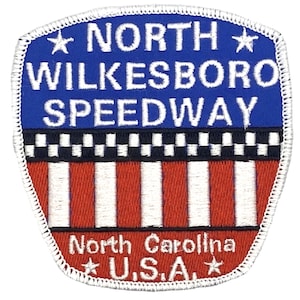 May include: A white embroidered patch with a blue background. The patch says "North Wilkesboro Speedway" with a star on either side of the text. Below the text is a checkered flag design and a red and white striped design. The bottom of the patch says "North Carolina" and "U.S.A." with a star on either side of the text.