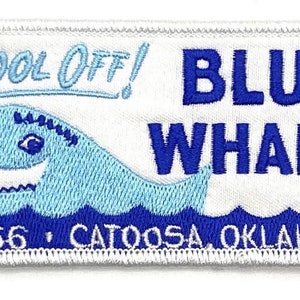 May include: White embroidered patch with blue text that reads "Cool Off! Blue Whale Rt. 66 Catoosa Oklahoma". The patch features a blue whale with a white outline and a blue wave design at the bottom.