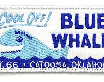 May include: White embroidered patch with blue text that reads "Cool Off! Blue Whale Rt. 66 Catoosa Oklahoma". The patch features a blue whale with a white outline and a blue wave design at the bottom.