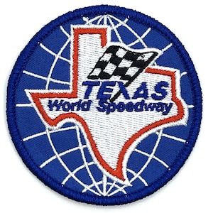 Op de afbeelding: Een geborduurde patch met een witte omtrek van de staat Texas met een geblokte vlag en de tekst "Texas World Speedway". De patch is blauw en wit.
