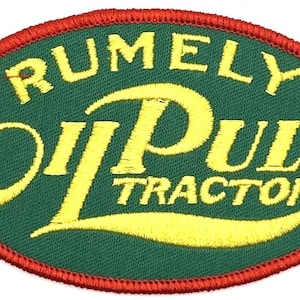 May include: Embroidered patch with the words "RUMELY Oil Pull TRACTOR" in yellow on a green oval. The patch has a red border. The patch is likely for a vintage tractor enthusiast.