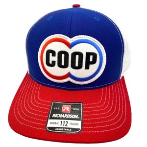 May include: A blue, red and white trucker hat with a white circle containing the word "COOP" in black lettering. The hat is made by Richardson 112 and is adjustable.