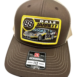 Può includere: Cappellino da camionista marrone e beige con un'auto bianca e nera e il testo "88 Dale Jarrett" su una toppa gialla. Il cappello ha un'etichetta nera con il testo "Richardson Original 112 Trucker Adjustable" su di essa.