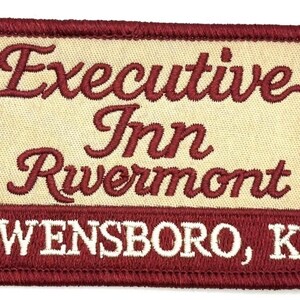 May include: A rectangular patch with a cream background and a maroon border. The patch features the words "Executive Inn Rvermont" in a script font, and "OWENSBORO, KY" in a sans-serif font.