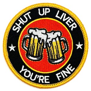 May include: A round, black and gold embroidered patch with the text "Shut Up Liver You're Fine" and a graphic of two beer mugs with foam on top.