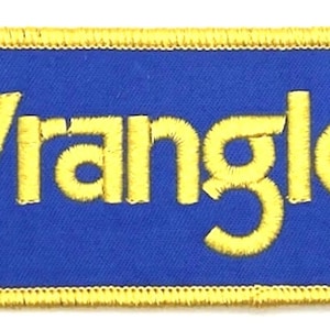 Puede incluir: Un parche bordado azul y amarillo con la palabra "Wrangler" en letras amarillas.