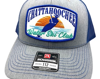 May include: A gray and blue trucker hat with a patch that says "Chattahoochee Water Ski Club" with a sunset and a person waterskiing. The hat is adjustable and has a Richardson logo.