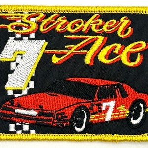 May include: A black embroidered patch with a red race car, the number "7" and the text "Stroker Ace" in yellow.