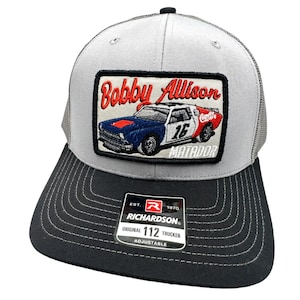 Könnte beinhalten: Graue und schwarze Trucker-Kappe mit einem Patch, auf dem ein rot-weiß-blaues Rennwagen mit dem Text "Bobby Allison" und "Matador" abgebildet ist. Die Kappe hat auch ein schwarzes Etikett mit dem Text "Richardson" und "112 Trucker".