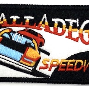 May include: A black and white embroidered patch with the text "Talladega Speedway" in red, yellow, and white. A red, yellow, and blue race car is shown driving on a white track.