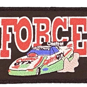 May include: A black embroidered patch with the word "FORCE" in red letters with white outlines. A green and white race car with the words "Castrol GT" and "Castrol" is shown below the word "FORCE".